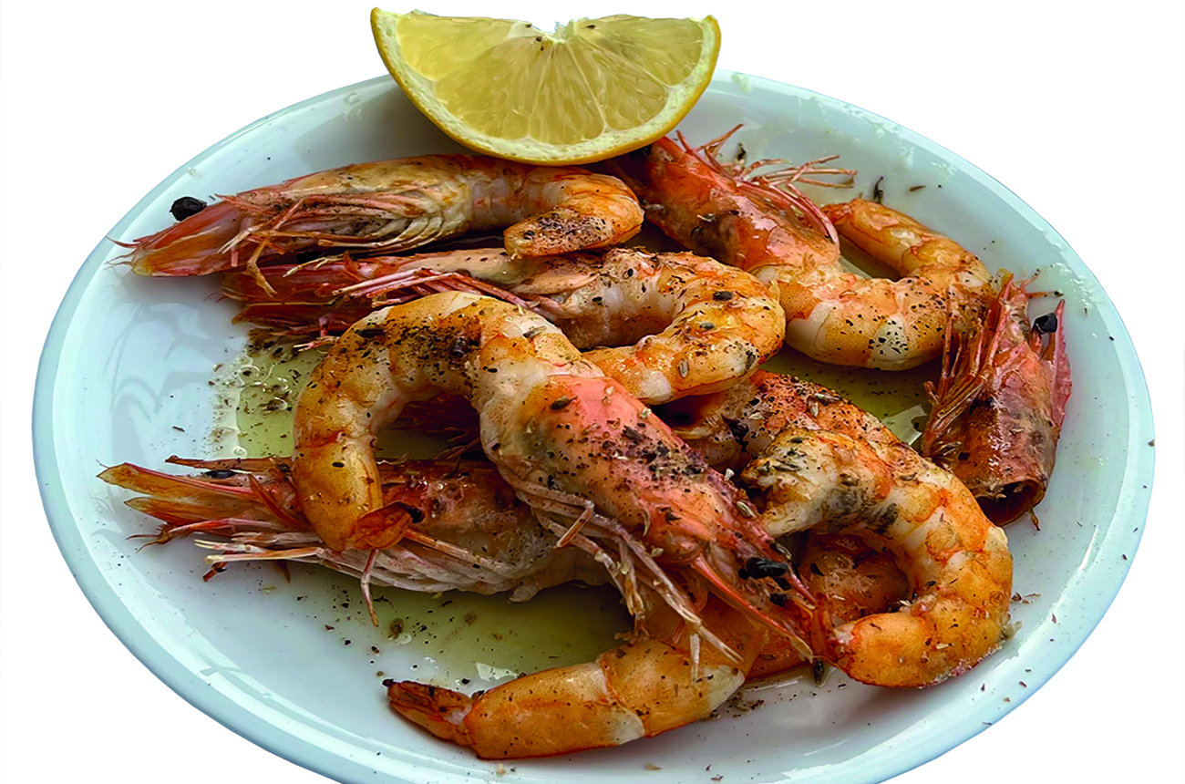 Grilled king prawns served with lemon on a plate in a restaurant setting. Seafood, fine dining, Mediterranean cuisine, gourmet meal, local food, travel, culinary tourism, Greek restaurant.