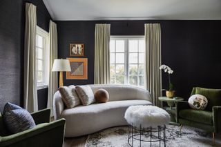 A black apartment living room idea with small curved cream sofa and cream drapes.