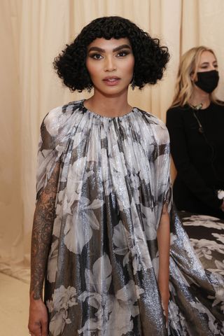 Chef Sophia Roe with a curly bob hairstyle in a long floral dress.