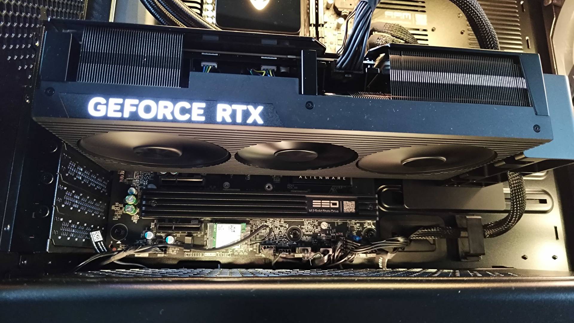 Close up of RTX 5090 with glowing GeForce RTX logo inside Alienware Area-51 PC.