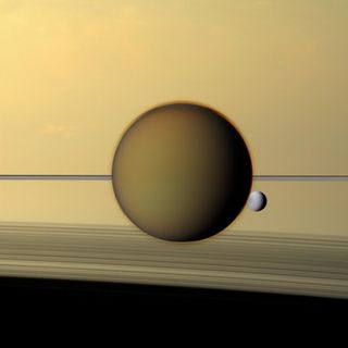 Studying areas such as Titan, a moon of Saturn (foreground) can give researchers ideas about how chemistry eventually created life.