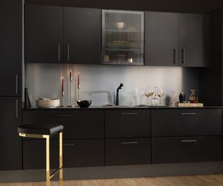 black kitchen units and worktop with aluminium splashback