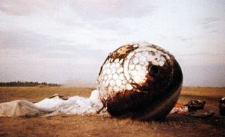Here the re-entry capsule of the Vostok 3KA-3 (also known as Vostok 1) spacecraft (Vostok 1) is seen with charring and its parachute on the ground after landing south west of Engels, in the Saratov region of southern Russia.