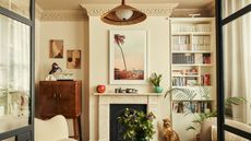 neutral living room with a painted warm yellow ceiling and coving, built in bookshelf vintage drinks cabinet and a marble fireplace