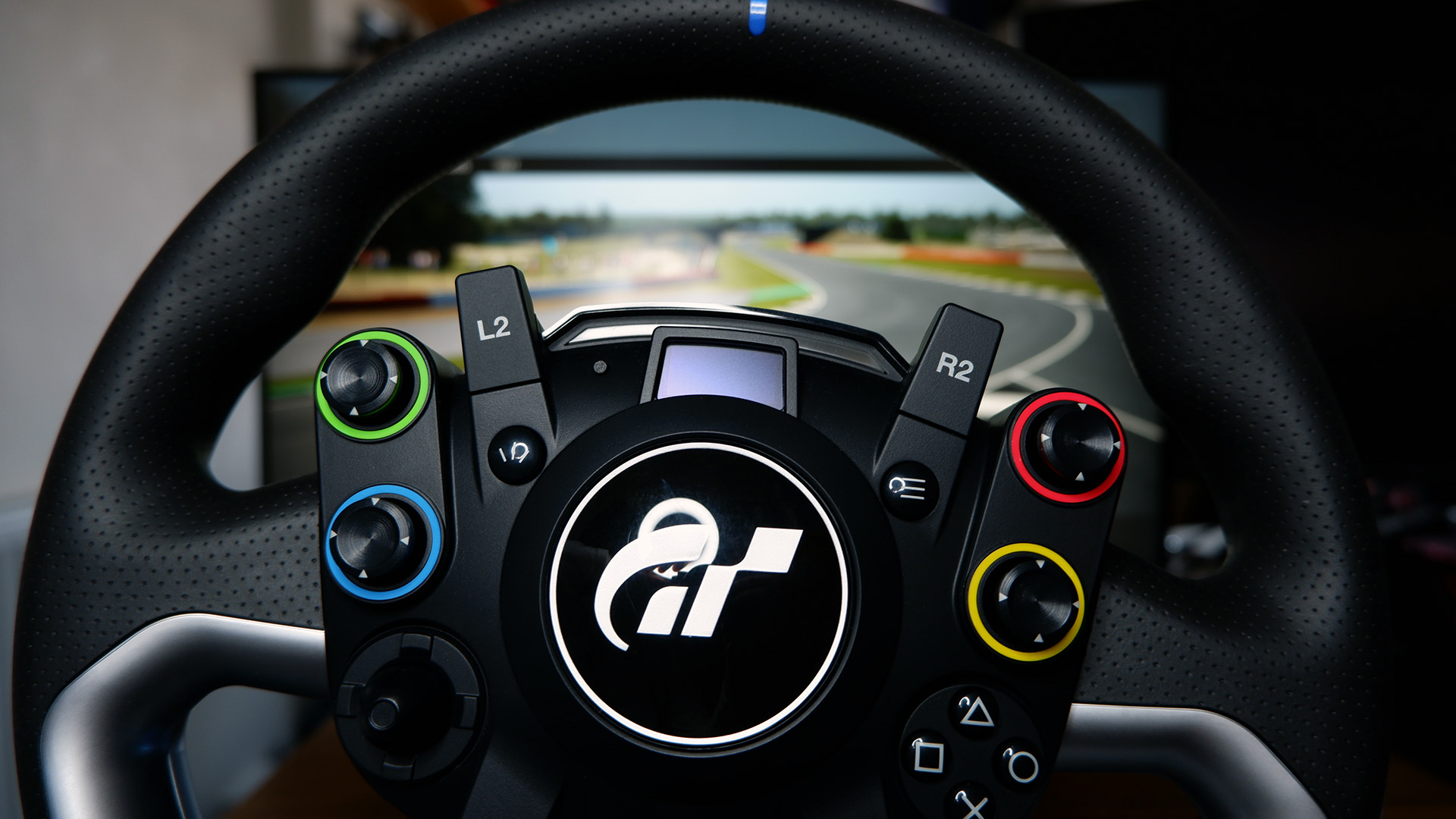 The Fanatec GT DD Pro racing wheel and wheelbase on a desk with monitor playing Assetto Corsa behind.