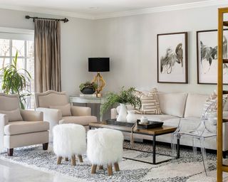 Scandi mono living room scheme with framed wall art, house plants, and sheepskin stools