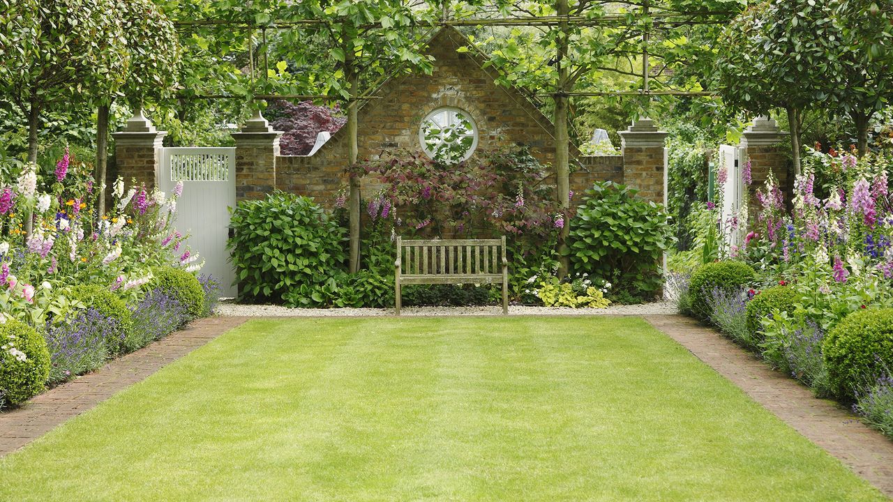 Neat lawn surrounded by flower beds with bench