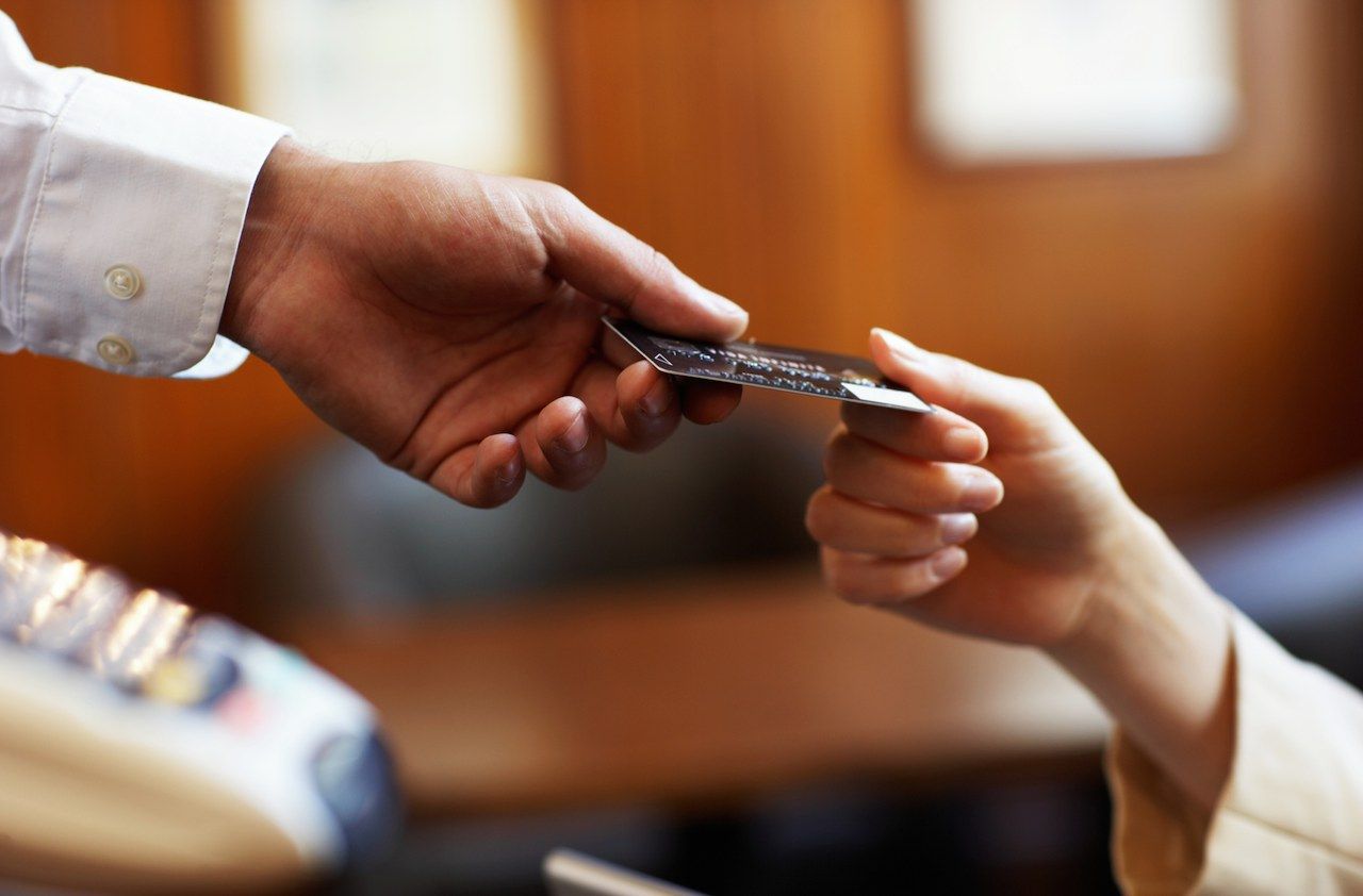 Young woman handing waiter credit card, close-up