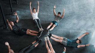 Group of people performing hollow body rock abs exercise