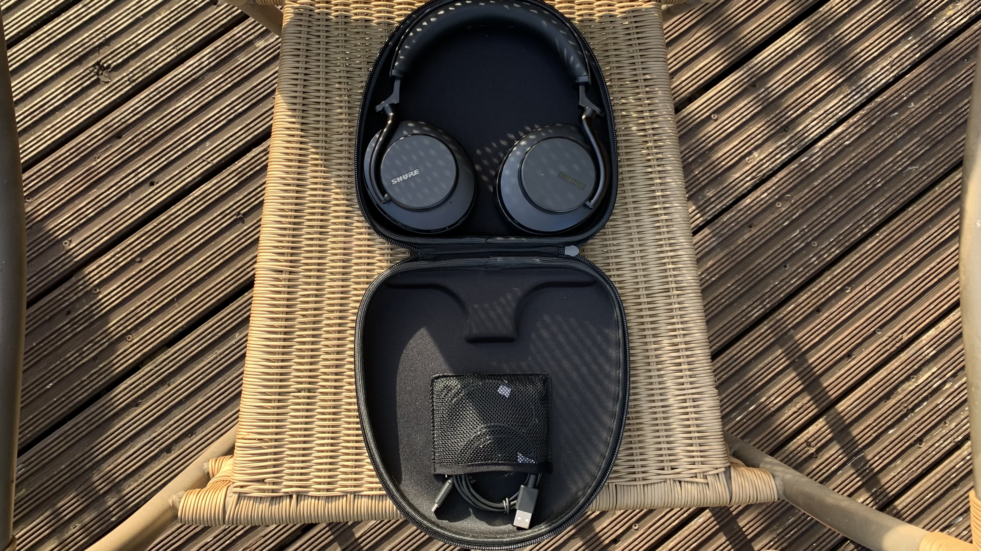 Shure Aonic 50 Gen 2 in their hard travel case, on a wicker chair
