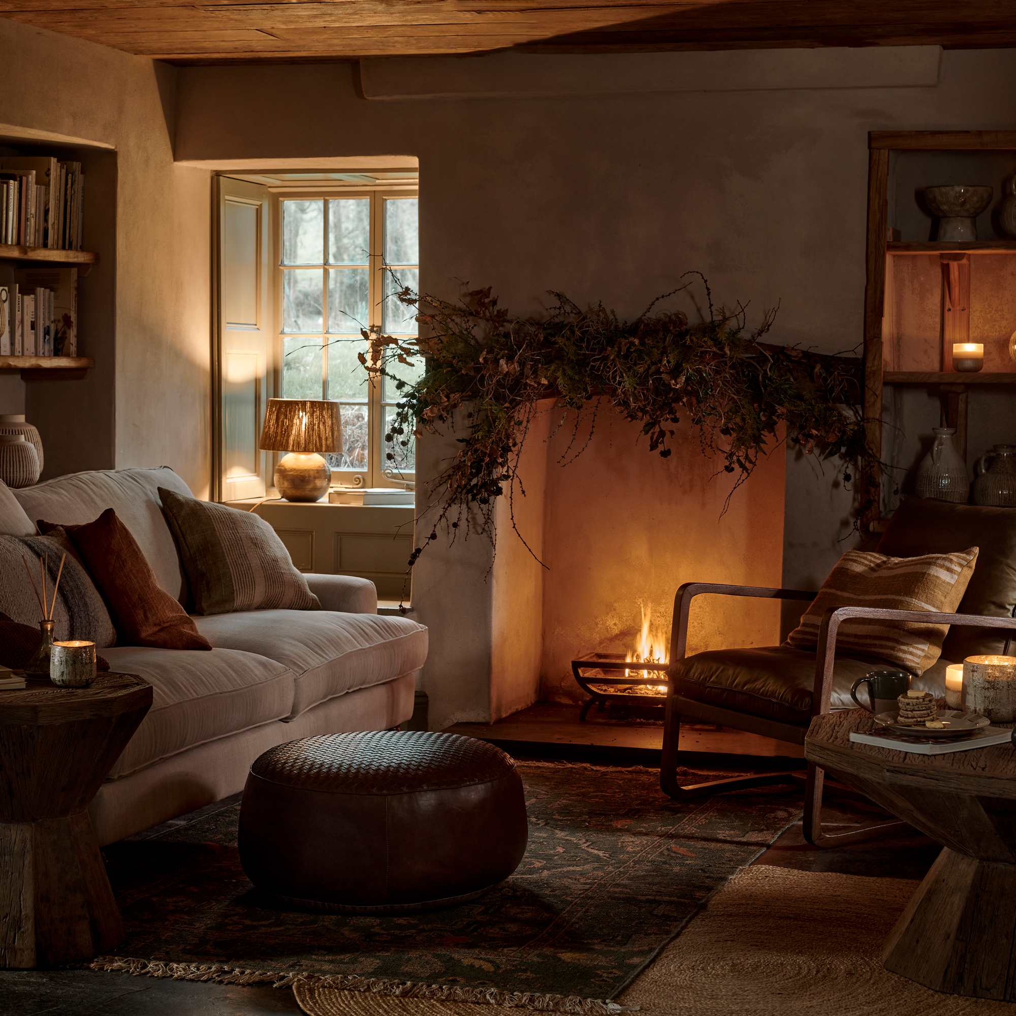 cosy living room with open fire and candlelight and lamp in window