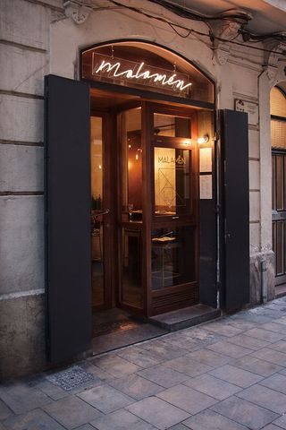 Large wooden and glass doors to the Malamén restaurant with the restaurant name above the door in lights.