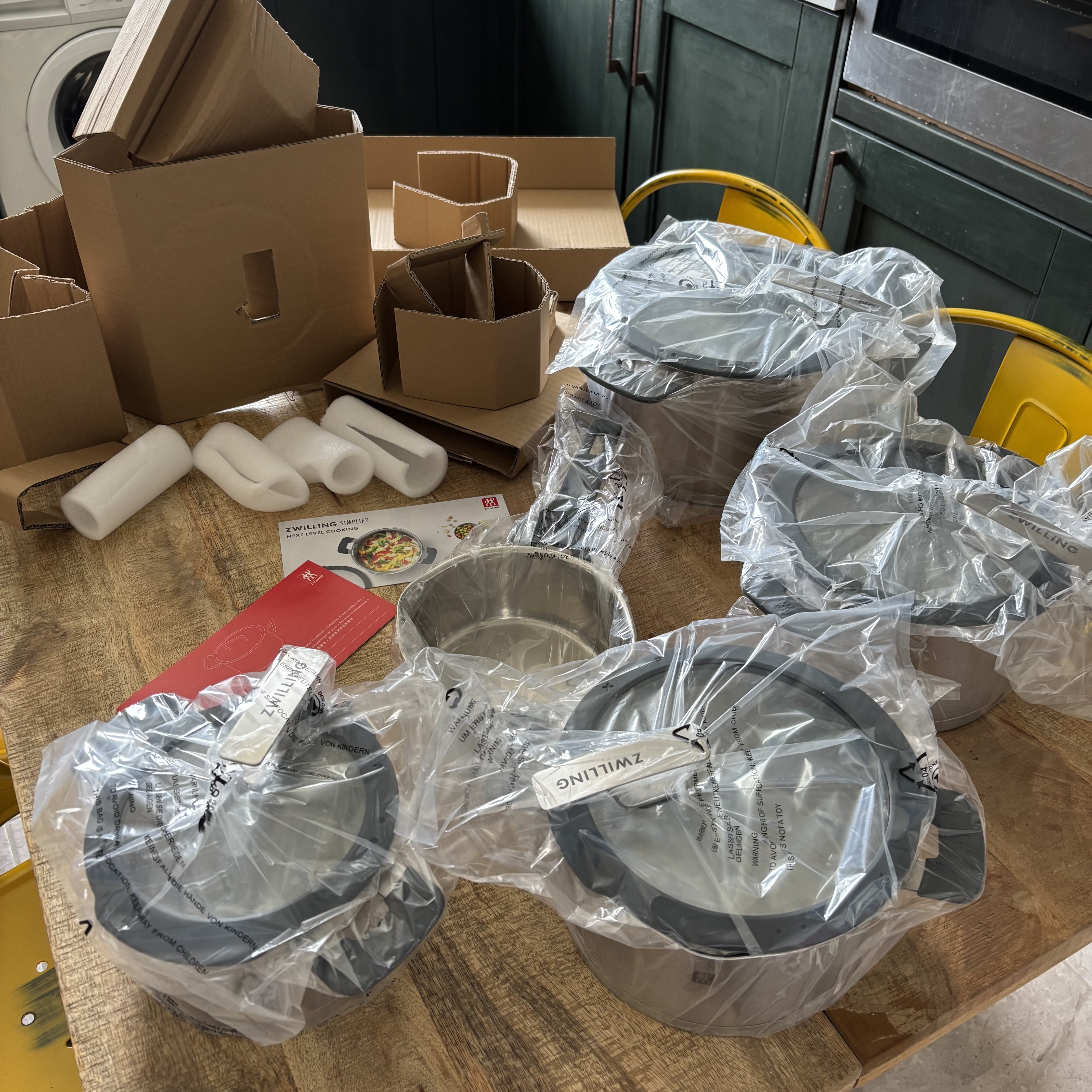 The packaging of the Zwilling Simplify Pot Set spread out on a kitchen table after unboxing.