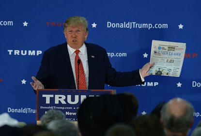 Donald Trump holds a copy of the New Hampshire Union Leader