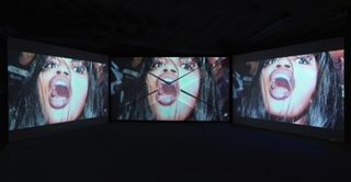 African woman with mouth open on three large TV screens