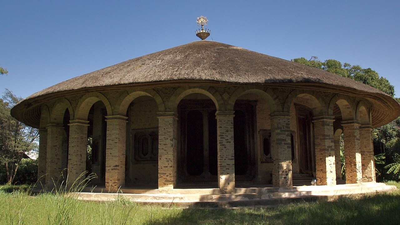 A photo of a round monastery with a thatched roof on a tropical island