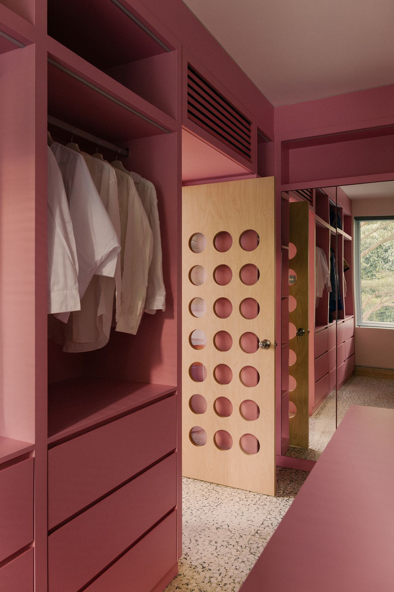 Image of a walk-in closet painted in a mid-tone pink color drench.