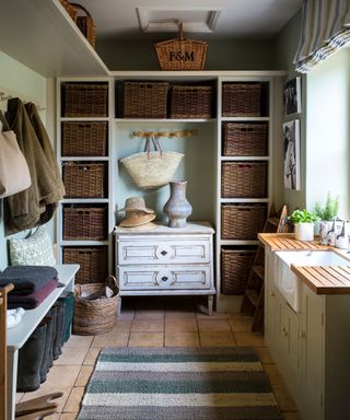 Boot room, with wicker storage baskets in tall shelving units, sink, stone flooring