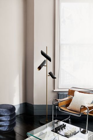 beige and charcoal scheme with black floor lamp, tan leather chair, black painted floor, glass coffee table