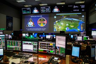 Colorful computer screens with scientific readouts stretch wall to wall in NASA's Orion mission control room.