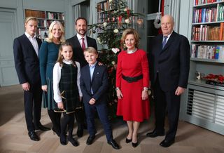 Norway's Queen Sonja and Norway's King Harald, Prince Sverre Magnus, Princess Ingrid Alexandra, Crown Prince Haakon, Crown Princess Mette-Marit and Marius Borg Hoiby posing in front of a Christmas tree and bookshelves