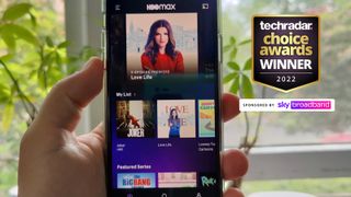 An image of a person holding a phone with the HBO Max app loaded and the TechRadar Choice Awards logo attached to it