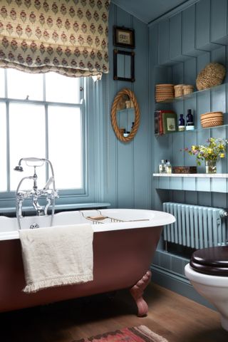 A small bathroom with a bright painted wall and red bathtub