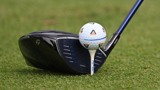 A close up of a driver behind a teed up golf ball