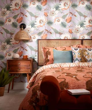 bedroom with wallpaper in lilac and terracotta with large floral print, wicker and wood furniture