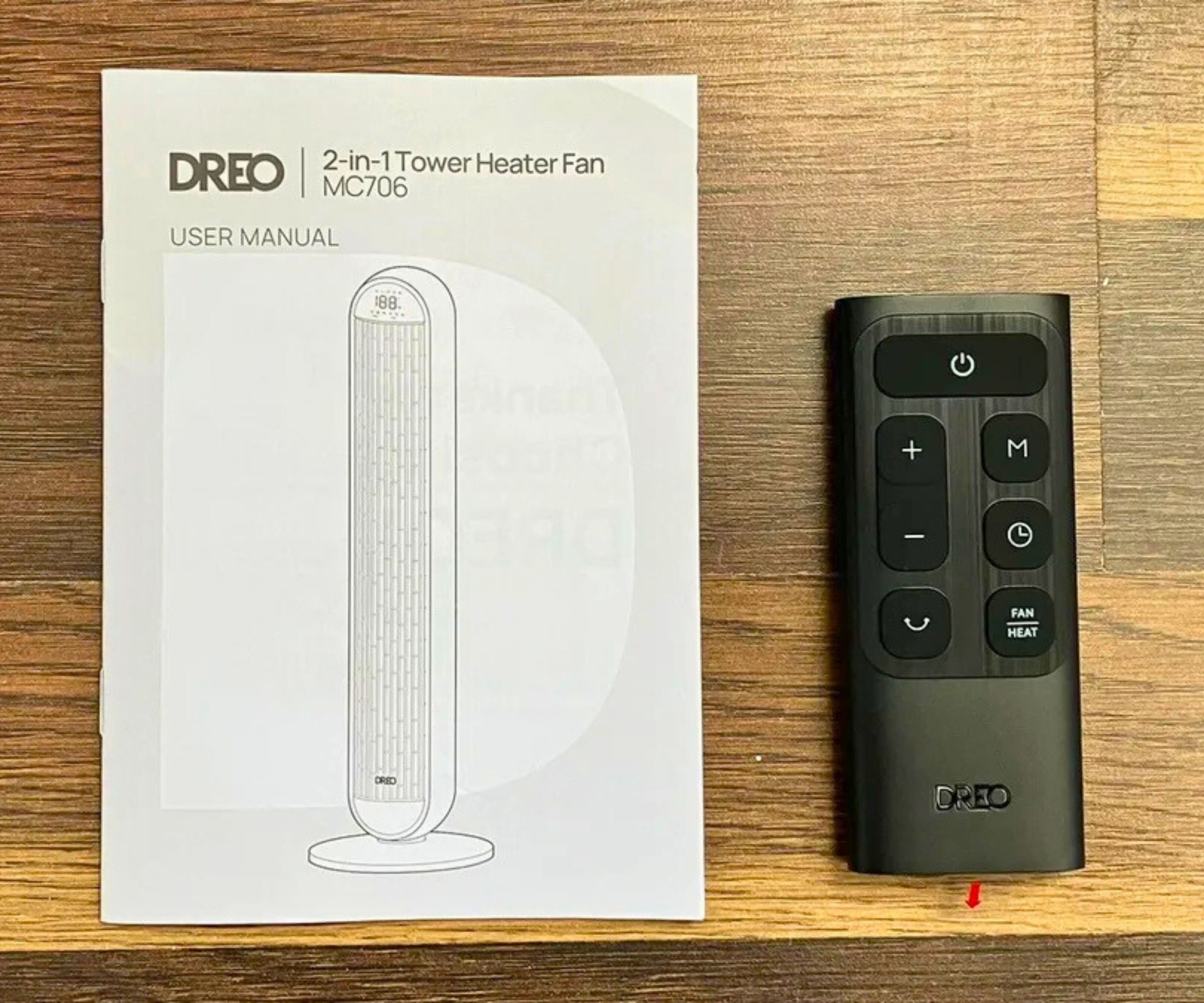 Photograph of Dreo 2-in-1 Tower Fan and Heater MC706 manual and remote control on wooden surface.