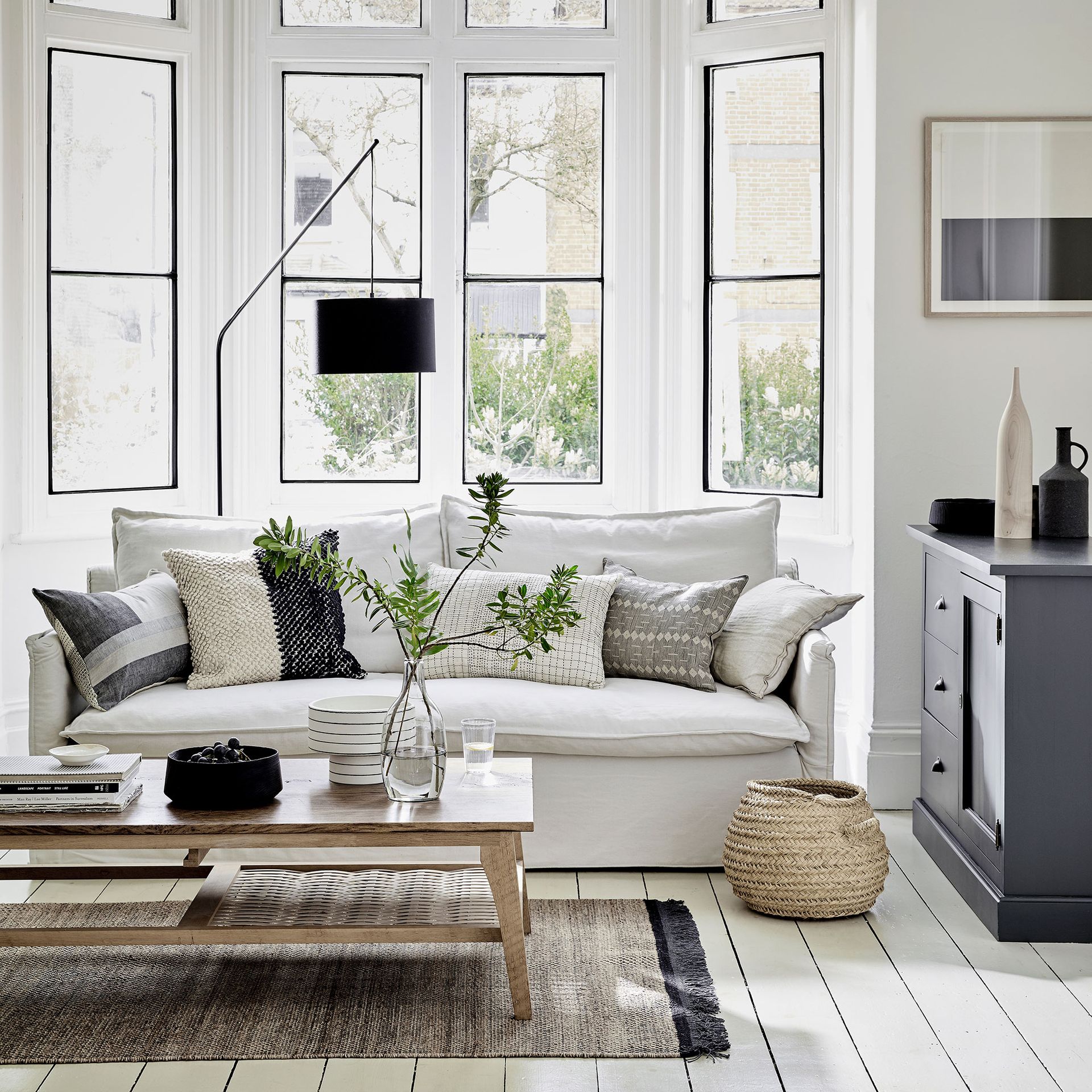 Living room with coffee table and white sofa in front of large bay window