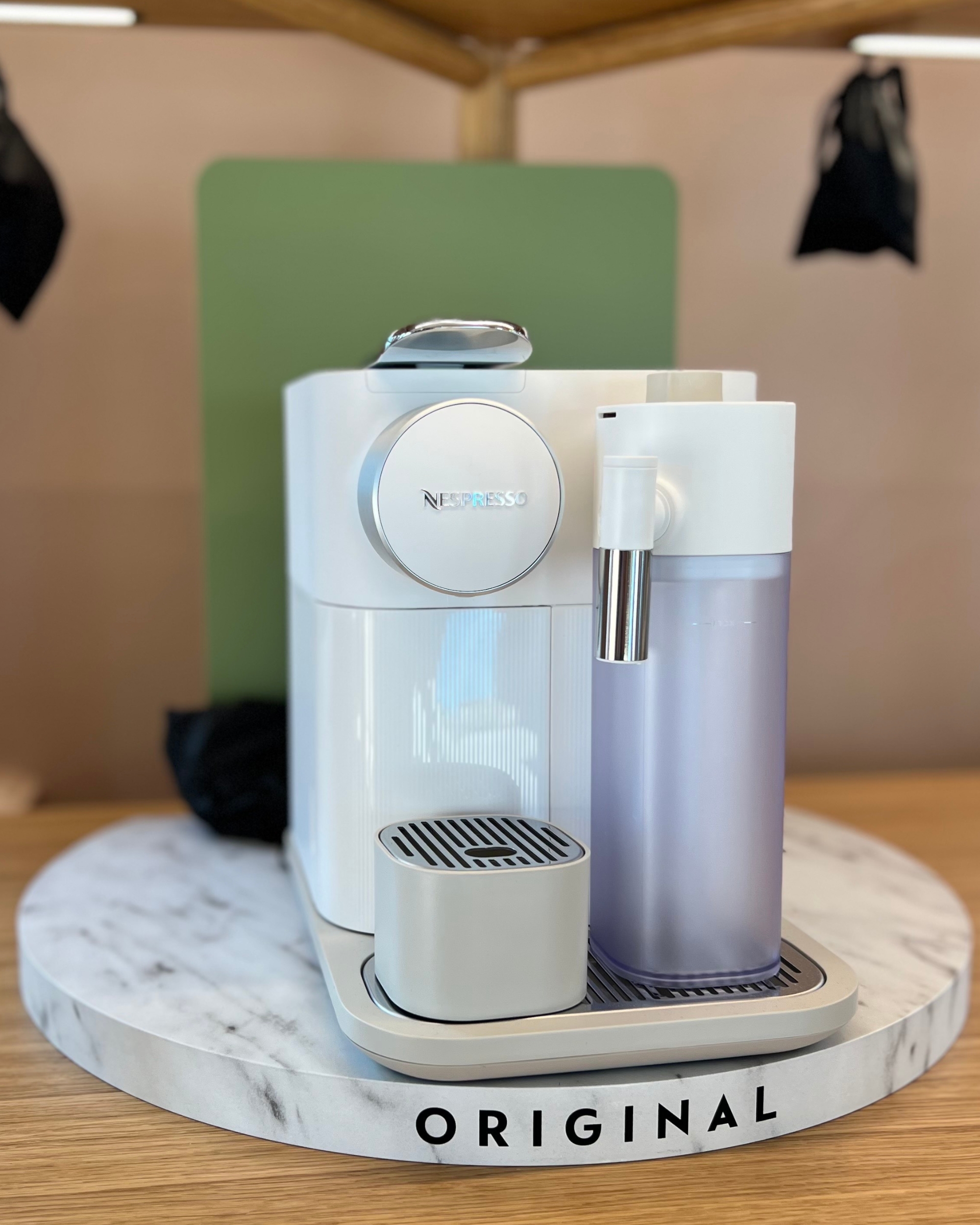 A white coffee machine on a round, marble base in a showroom.
