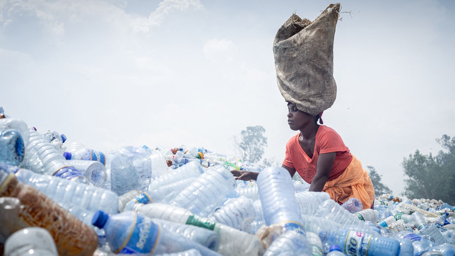 A woman sorts through piles of plastic bottles at the Mubone landfill while searching for charcoal fragments and recyclable materials to sell in the local market, in Bujumbura, Burundi
