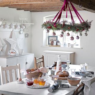 Christmas wreath with pink and silver bauble hanging from wooden support beam in kitchen