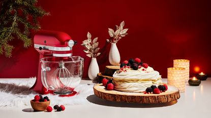 The KitchenAid Artisan stand mixer in a Christmas set with a meringue dessert and candles around it