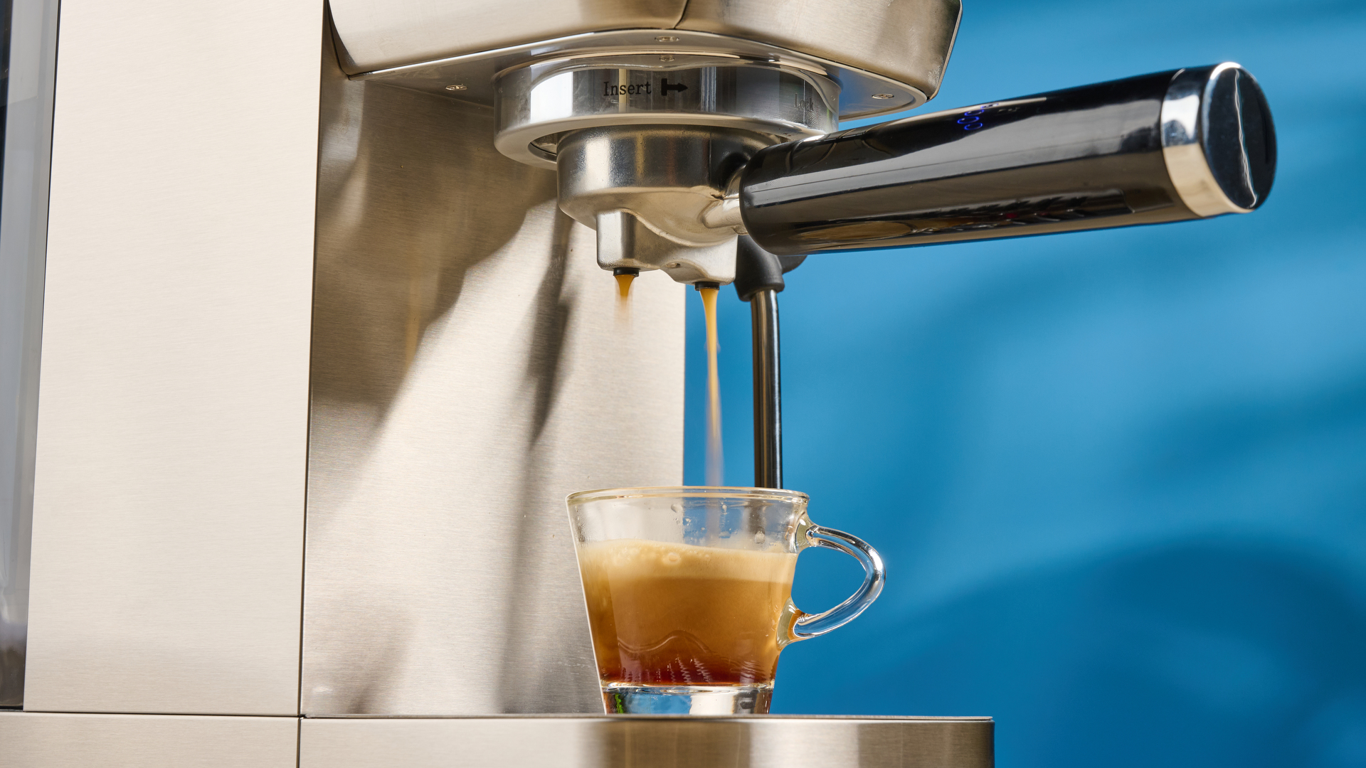 the casabrews 3700 essential espresso machine photographed against a blue background in stainless steel