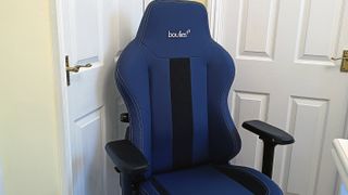 A blue leather Boulies Master Chair standing on a wooden floor in front of a white door
