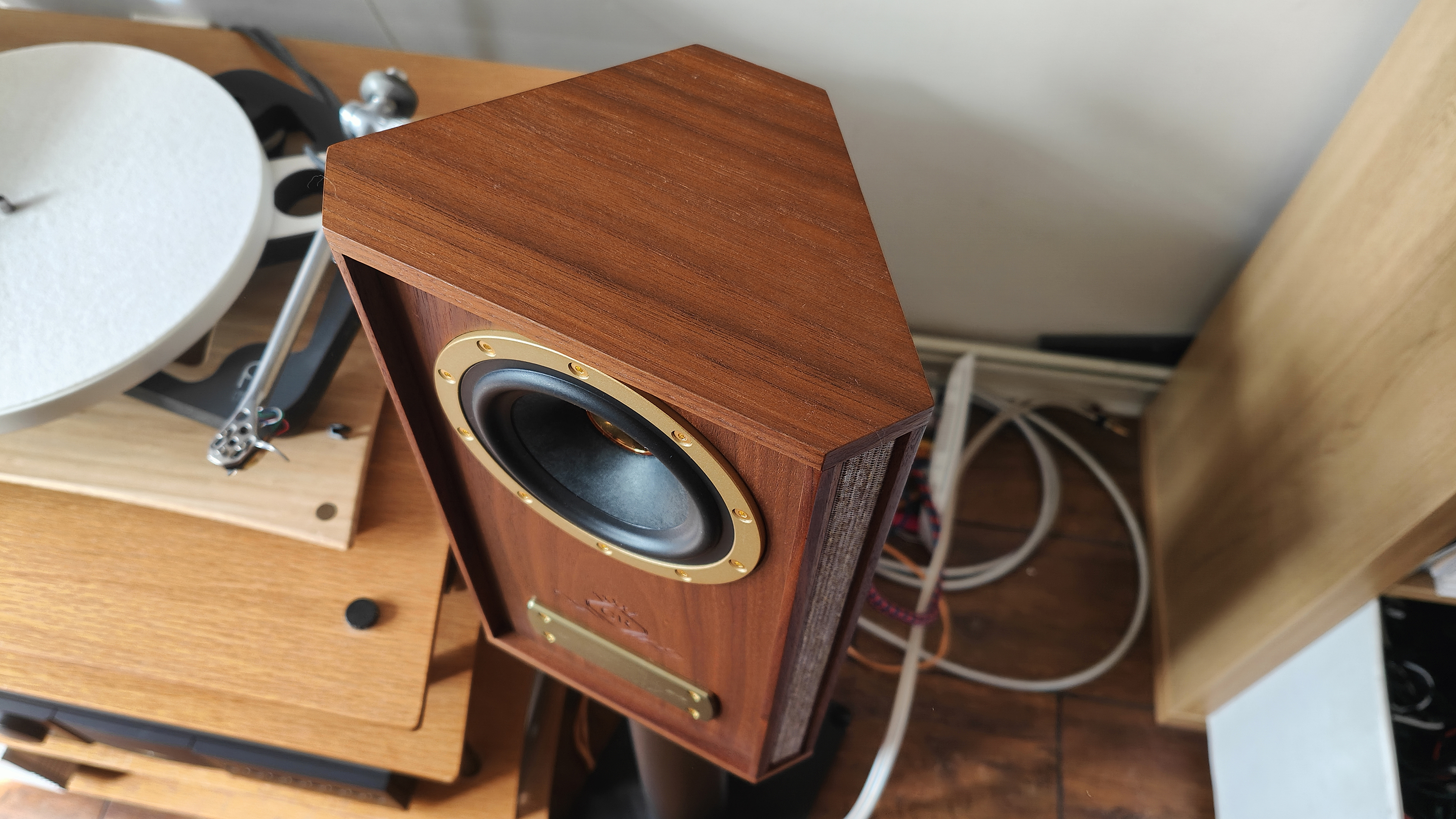 The Tannoy Autograph Mini pictured in a room next to a wooden sideboard and a record player