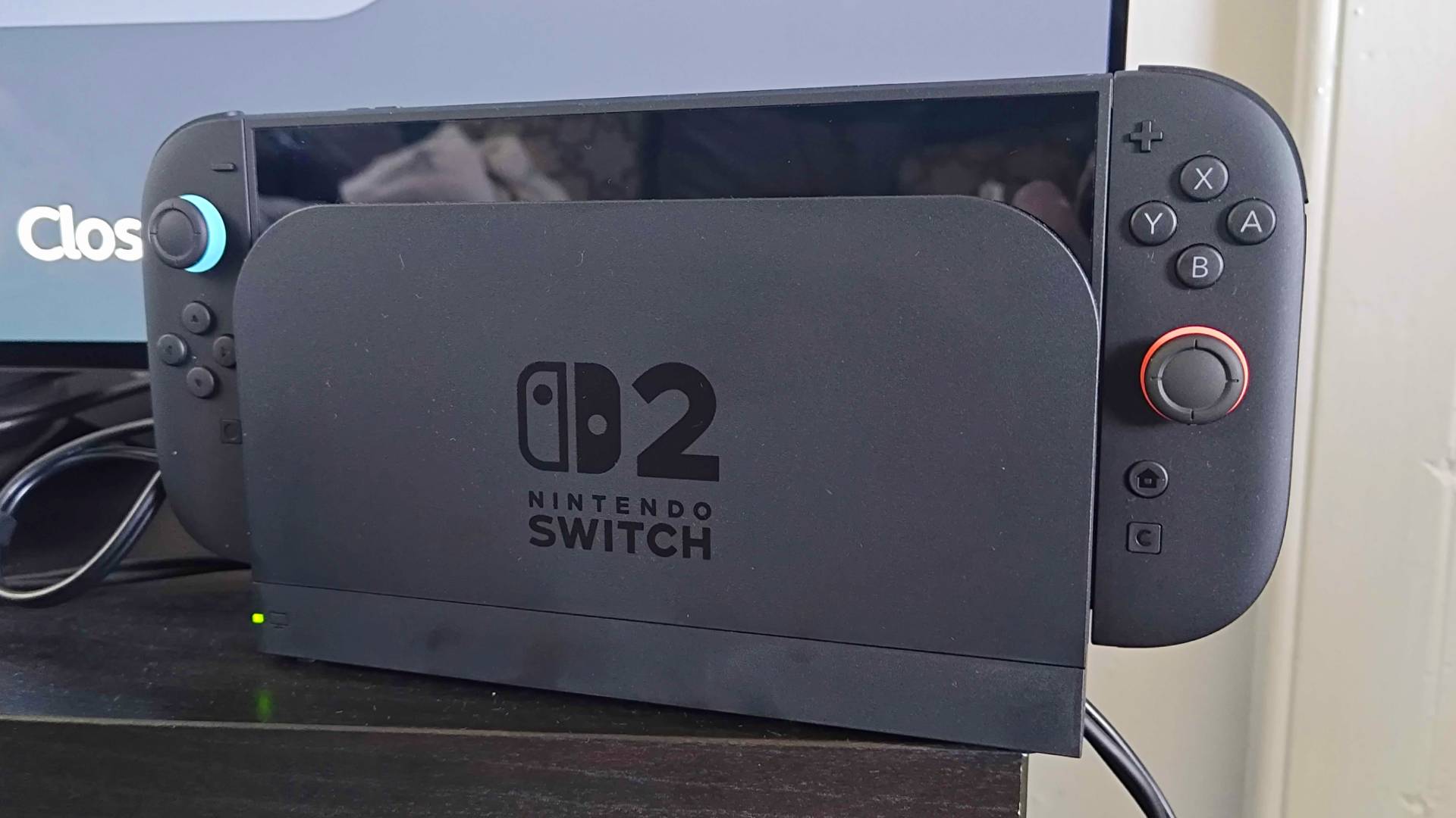 Nintendo Switch 2 connected to docking station on black TV unit.