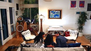 A family sits in front of a Glowforge Plus, with various objects surrounding them that have been engraved and cut using the Glowforge Plus machine.