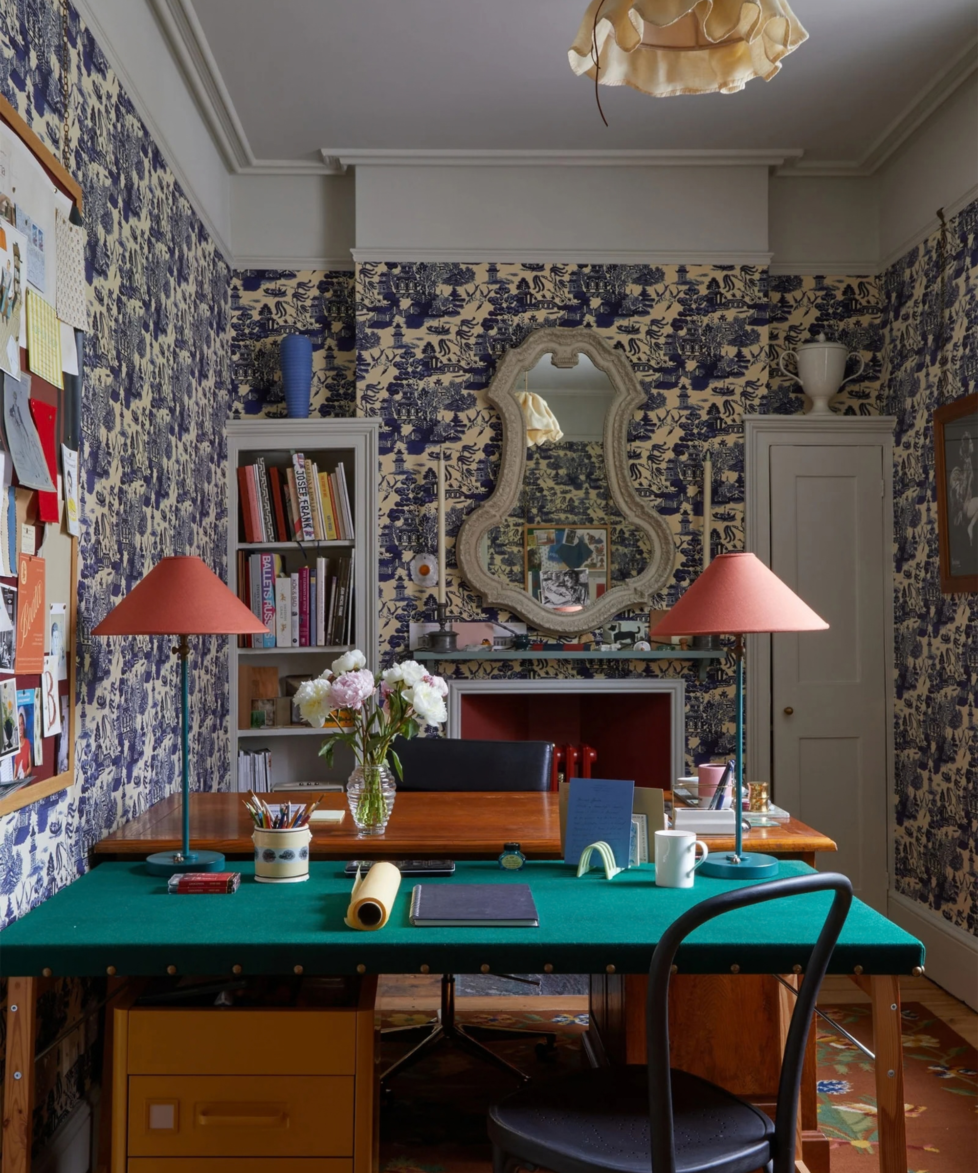 an office with a green desk, two table lamps, and blue toile wallpaper