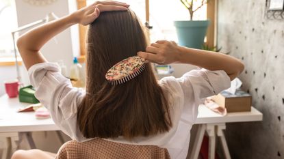 woman brushing her hair in front of the mirror