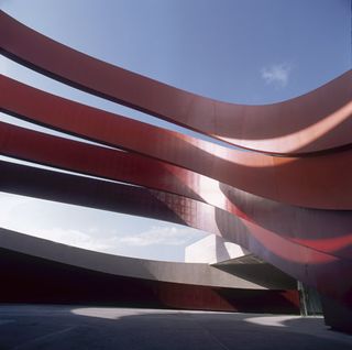 The building's massive curved ribs cling to the core like bright red slabs of steel baleen.
