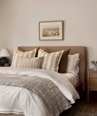 Neutral bed with striped headboard, patterned cushions and quilt