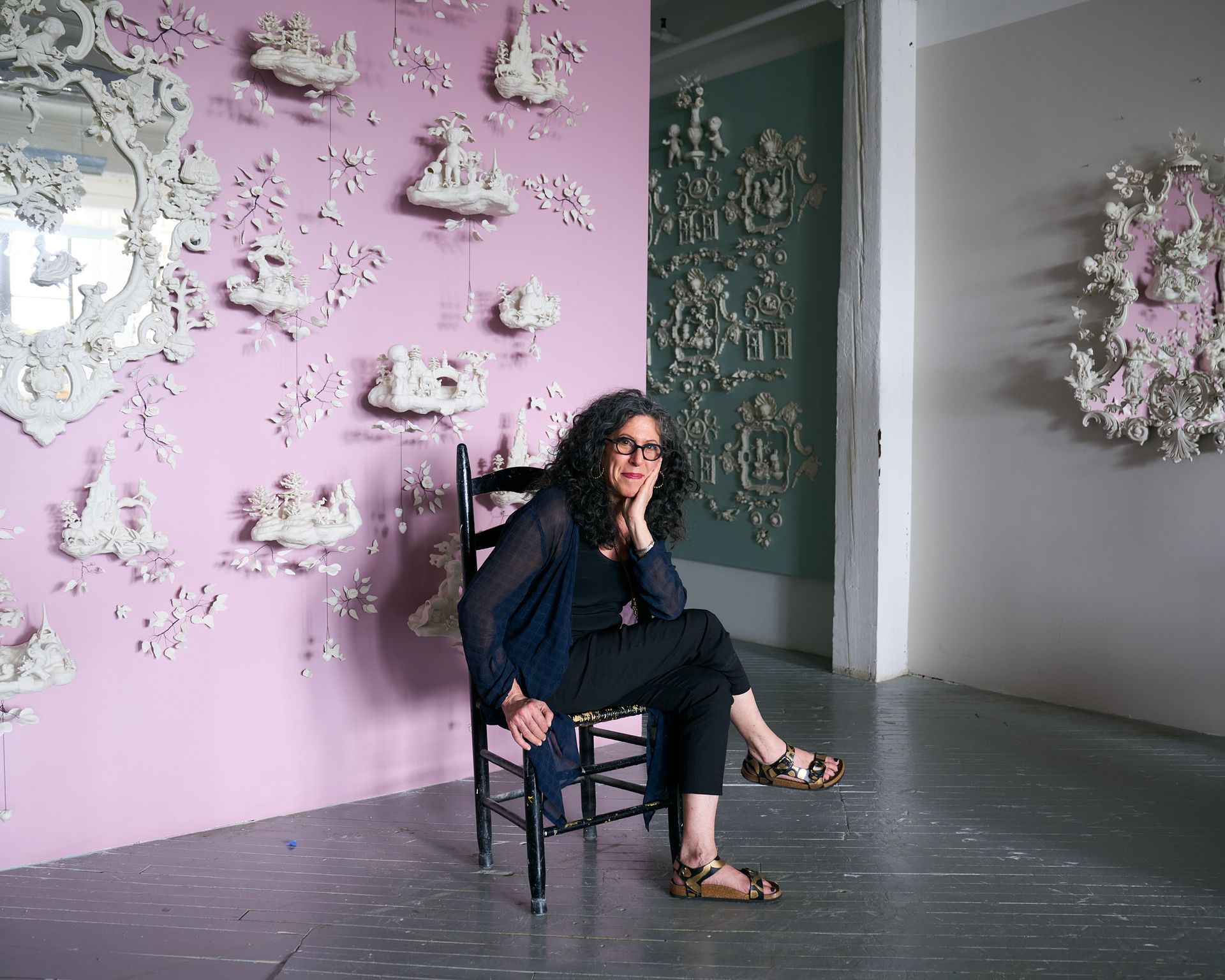 woman on chair in front of a wall hung with porcelain miniatures