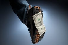 An outdoor boot or shoe with a dollar bill stuck to the bottom of it
