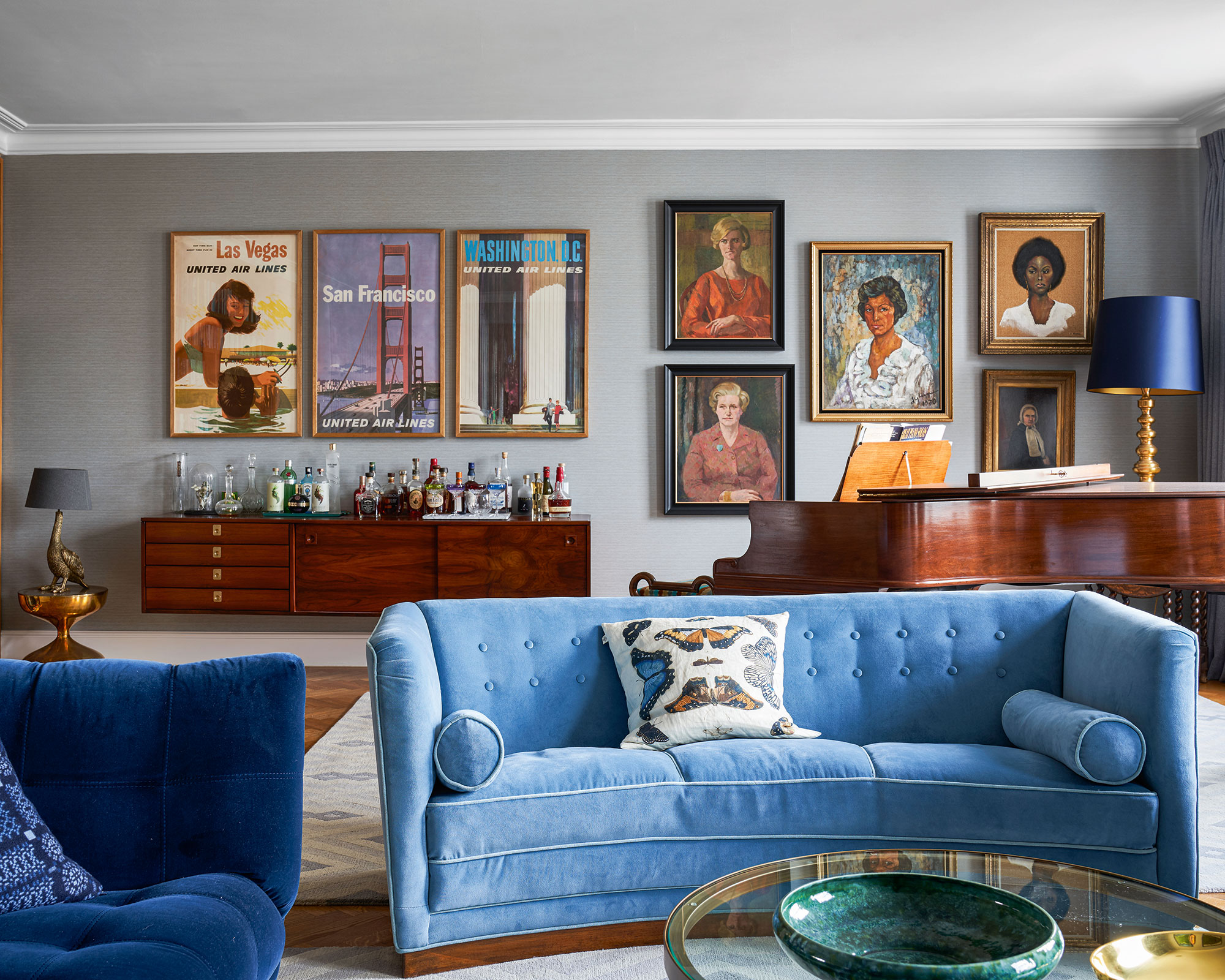 Neutral living room ideas illustrated with a blue velvet sofa and pale gray gallery wall.