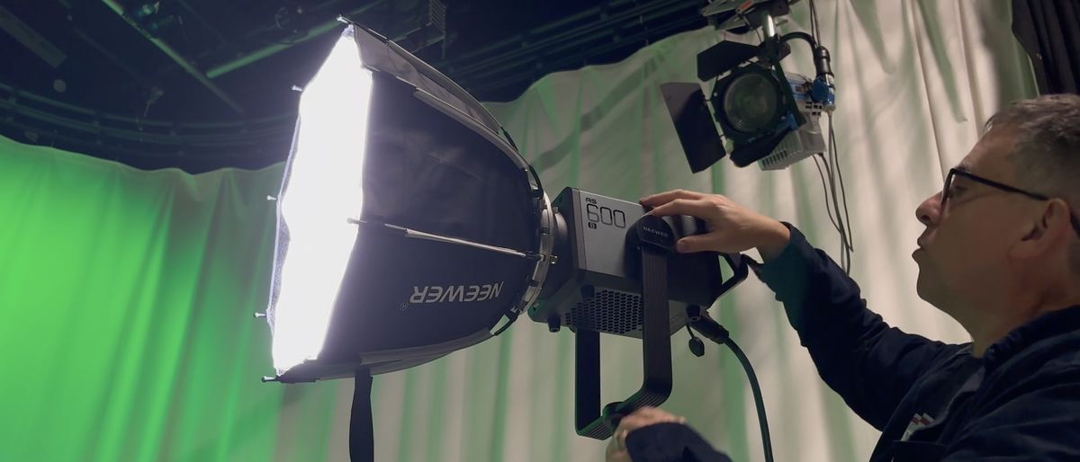 Neewer AS600B video light in a studio being adjusted by a person