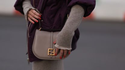 Close up of street style image showing woman&#039;s hands wearing red nail polish