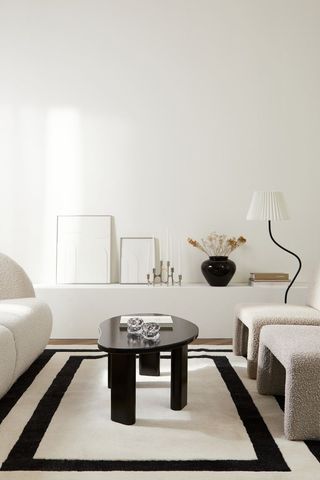 White tufted wool area rug with black accent border from H&M Home.